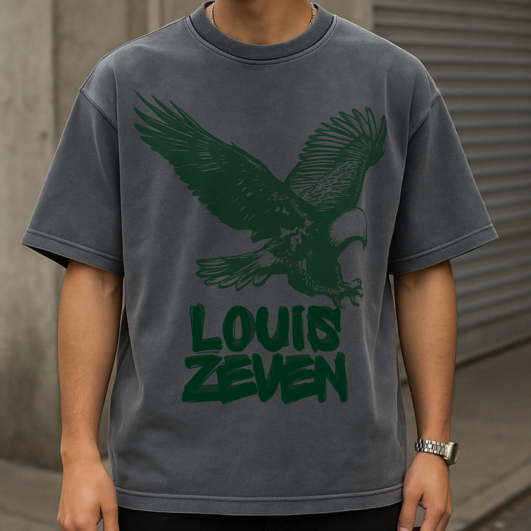 Man draagt grijs Louis Zeven boxy shirt met adelaar-print, streetwear stijl voor heren