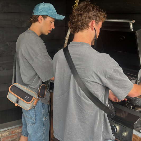 Man draagt grijs Louis Zeven boxy shirt met adelaar-print. Ook draagt hij een nylon messenger bag